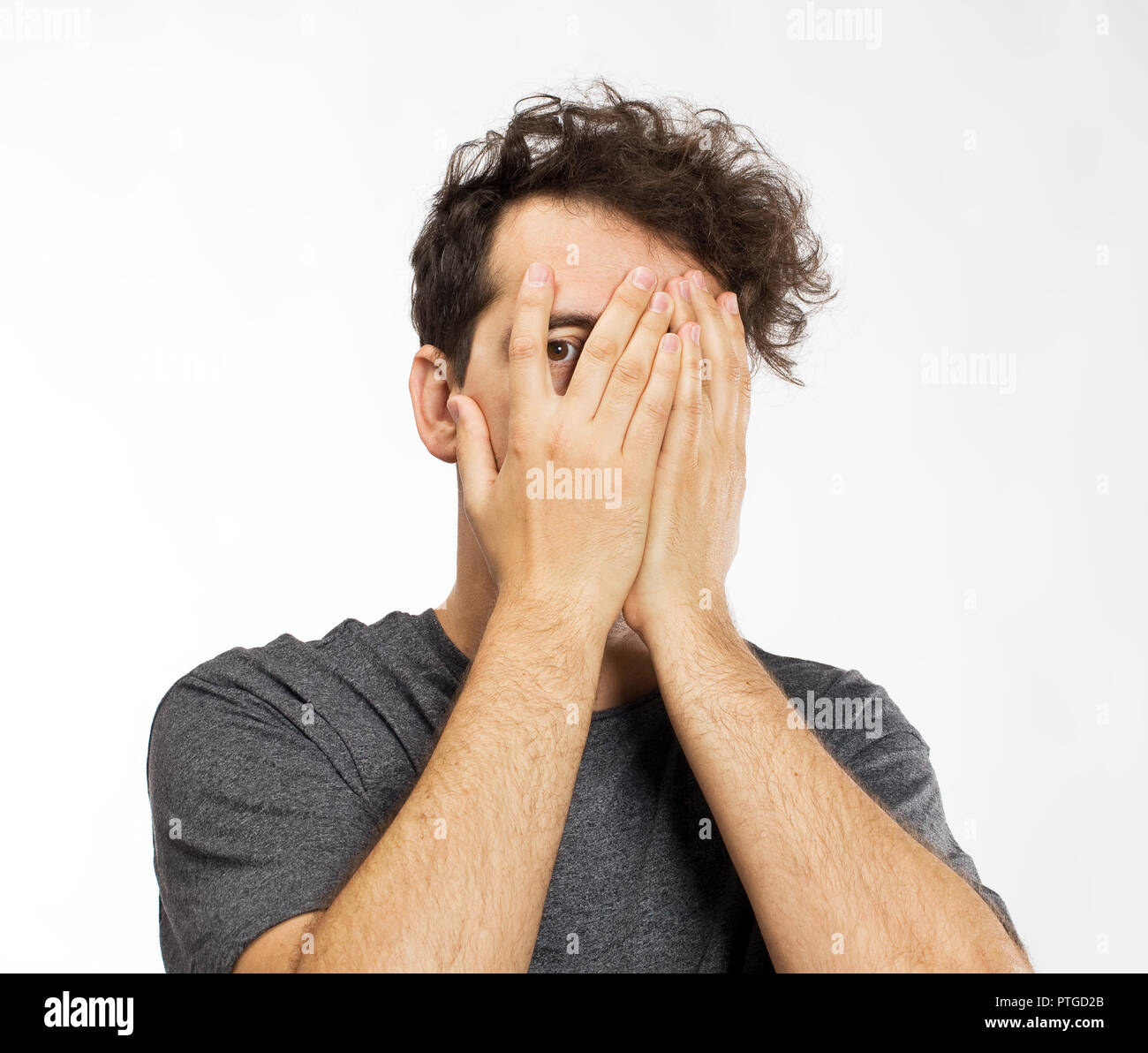 Giovane uomo bloccando il viso con le mani Foto Stock