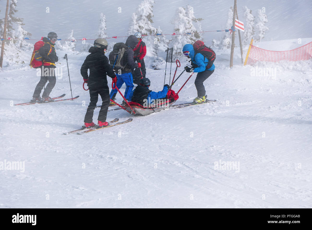 Ski team di soccorso con slitta barella, porta aiuto a sciare durante cattive condizioni meteorologiche. Foto Stock