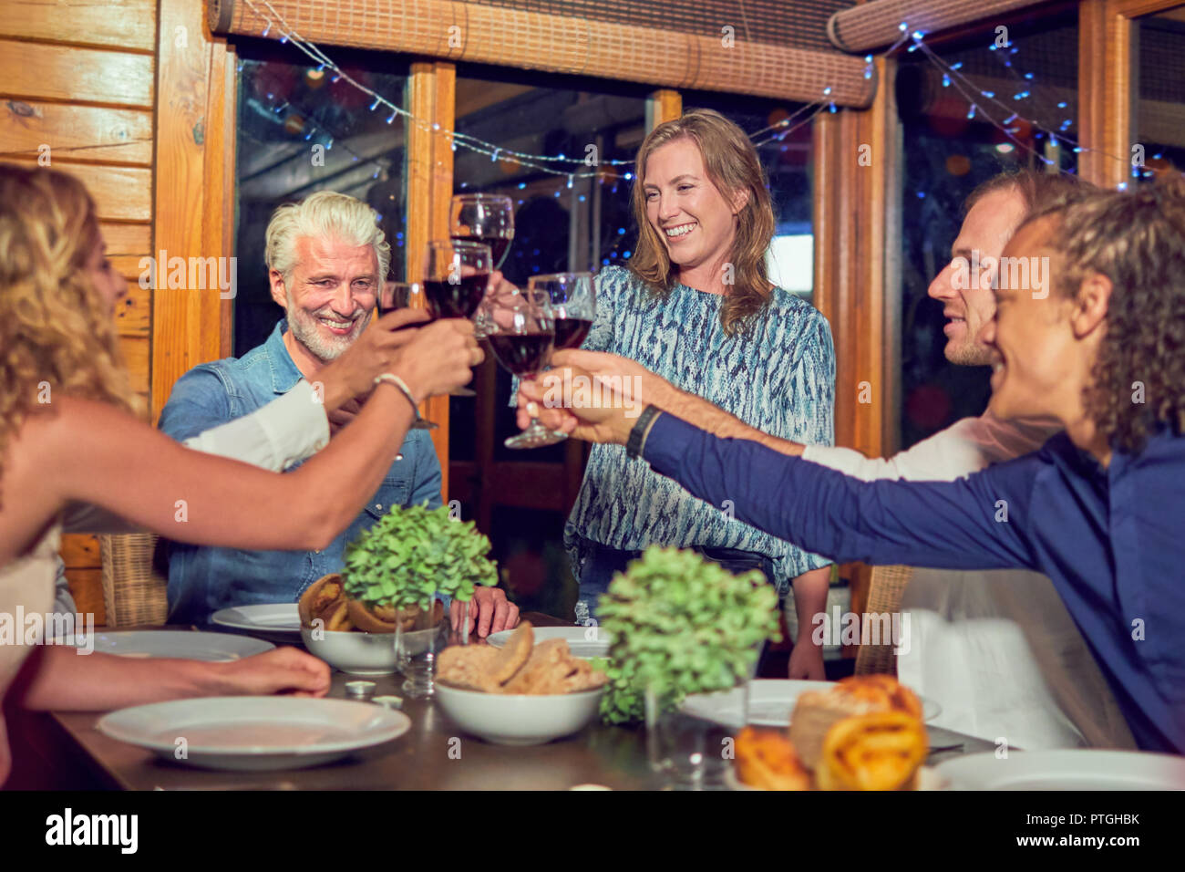 Amici celebrando, bere vino rosso e di gustare la cena in cabina Foto Stock