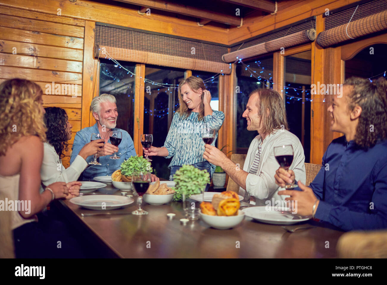 Amici celebrando, bere vino rosso e di gustare la cena in cabina Foto Stock