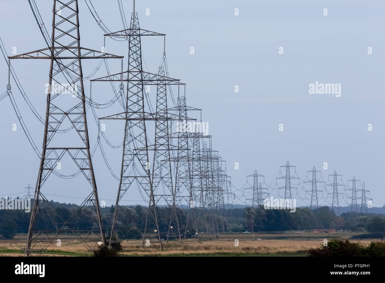Elettricità piloni o torri di trasmissione che porta di linee elettriche ad alta tensione e a cavi sospesi al di sopra di terra come parte della rete nazionale di distribuzione alimentazione di rete Foto Stock
