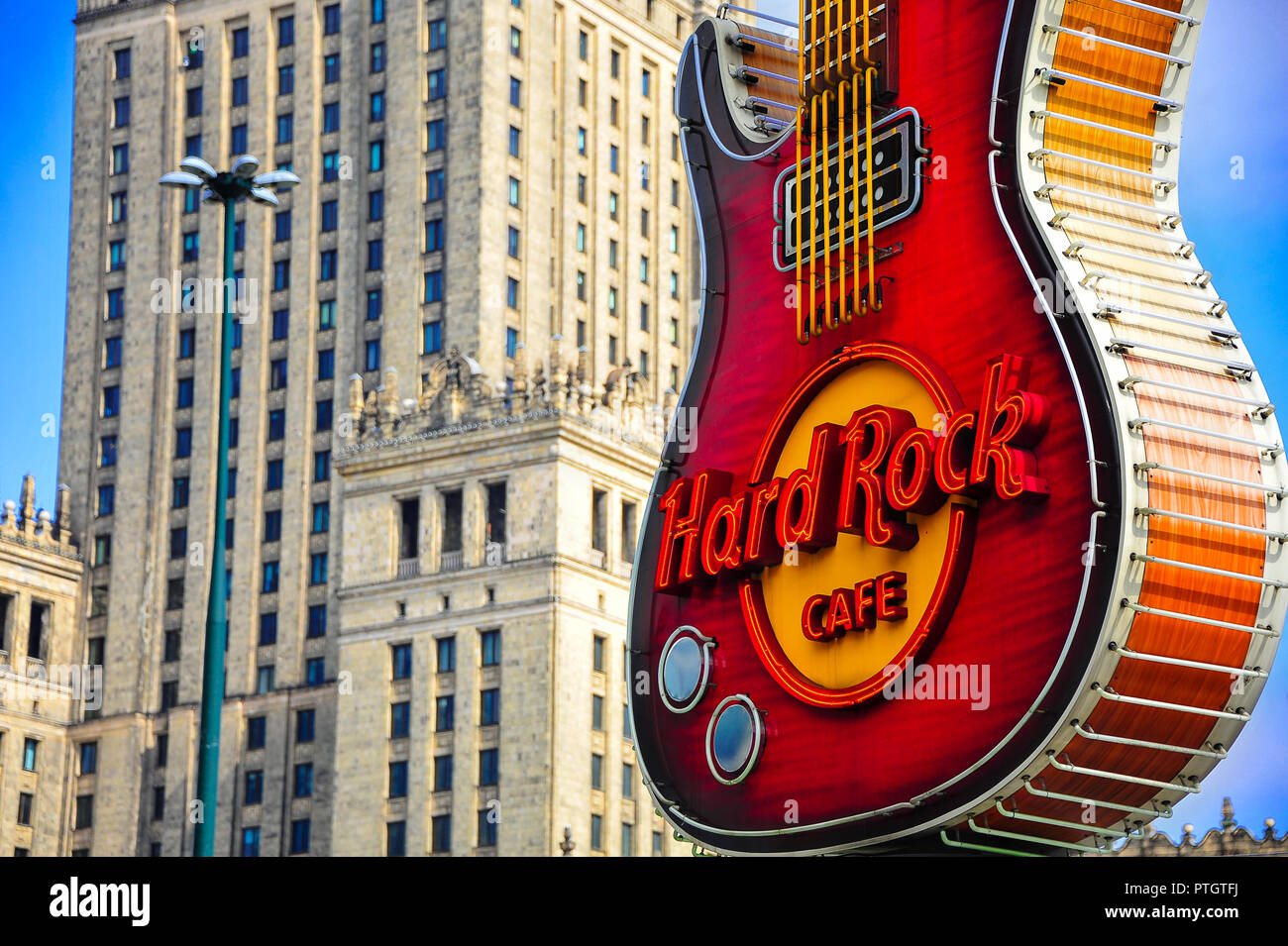 La leggendaria chitarra billboard sagomato di Hard Rock Cafe a Varsavia,  Polonia, con il palazzo della cultura dietro Foto stock - Alamy