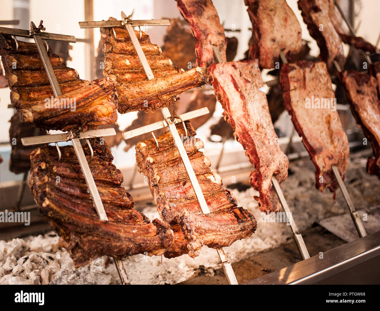Asado, barbecue tradizionale piatto in Argentina, carne arrosto di manzo cotta su griglie verticali collocati intorno al fuoco Foto Stock