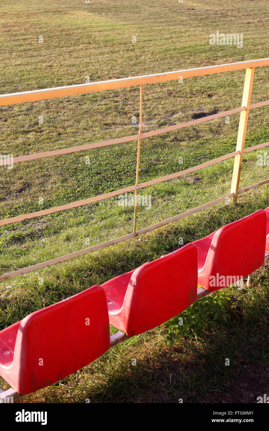 Tre vuoto, sedi rossa rivolta verso il campo di calcio di inizio autunno Foto Stock