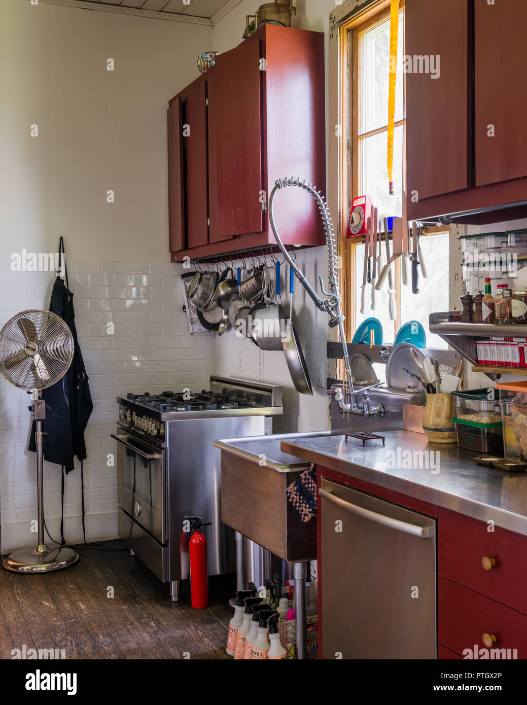 Memorizzazione nella piccola cucina dipinta fienile tradizionale in rosso con vasi appesi sul filo ritorto appendiabiti fornello di cui sopra Foto Stock