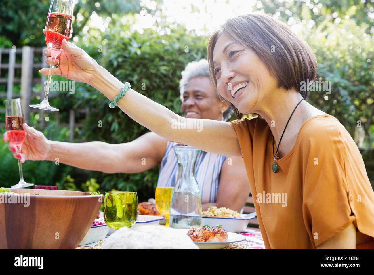 Felice active senior donne tostare vino rosato al party in giardino Foto Stock