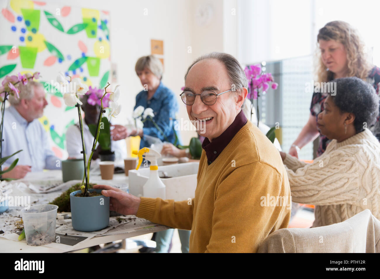 Ritratto sorridente e fiducioso senior attivo uomo godendo di decorazione floreale di classe Foto Stock