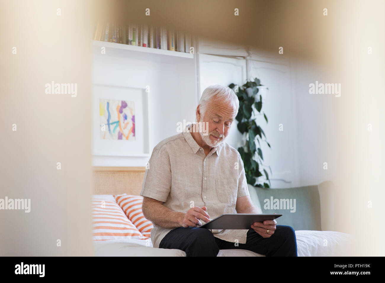 Senior uomo con tavoletta digitale sul letto Foto Stock