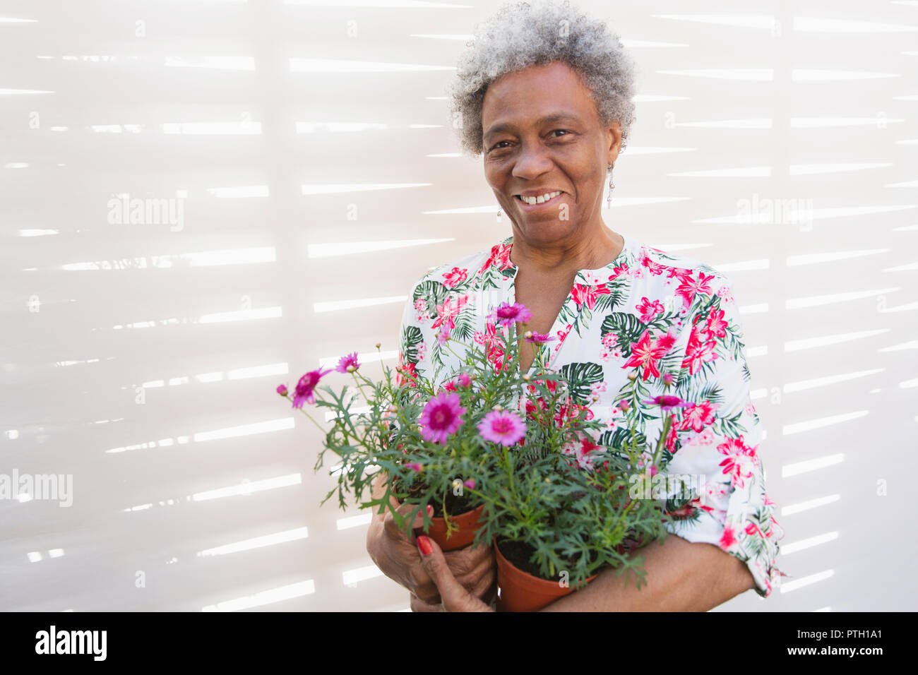 Ritratto sorridente e fiducioso senior attiva donna giardinaggio, i vasi da fiori di contenimento Foto Stock