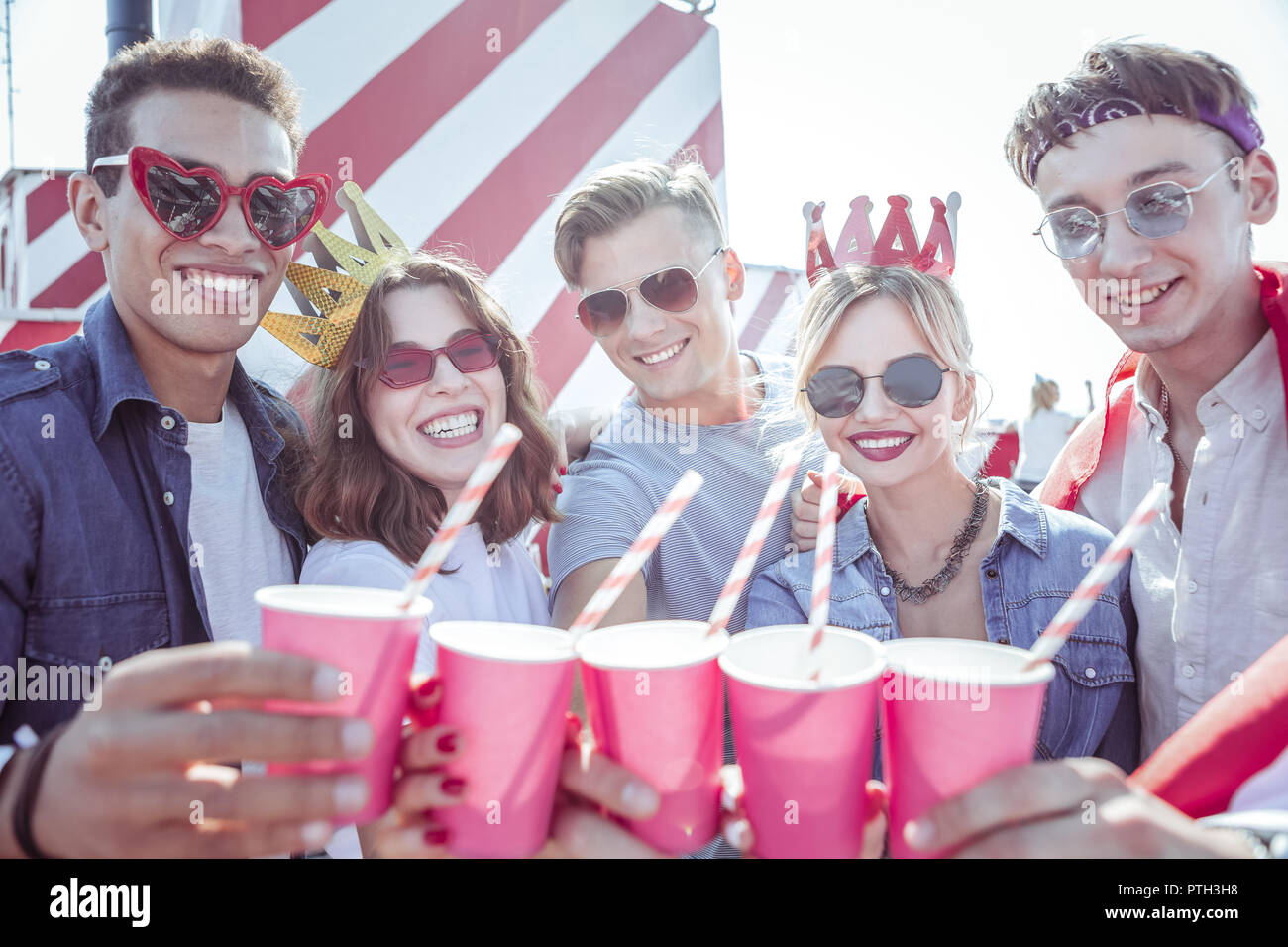 Gli studenti gioiosa dimostrando loro tazze rosa sulla fotocamera Foto Stock
