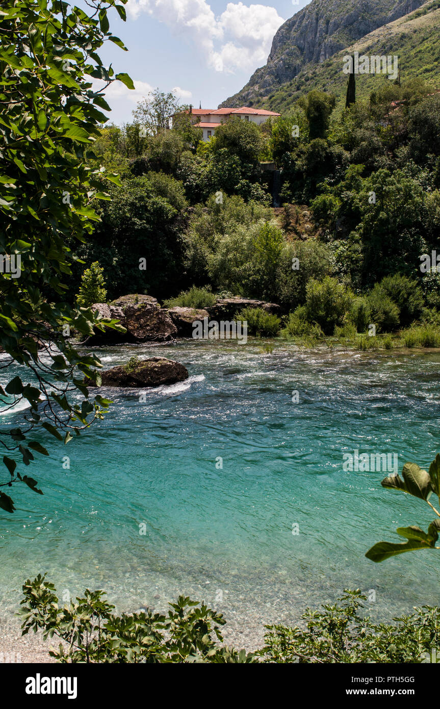 Mostar Bosnia Erzegovina: lo skyline della città vecchia si vede dal verde e trasparenti acque del fiume Neretva Foto Stock