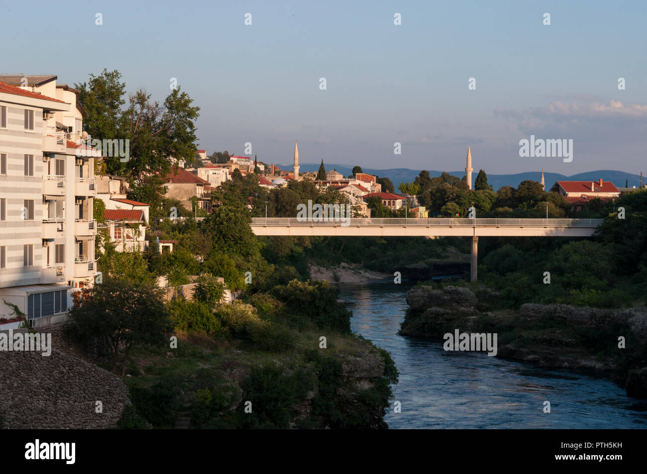 Mostar Bosnia Erzegovina: lo skyline della città vecchia si vede dal verde e trasparenti acque del fiume Neretva Foto Stock