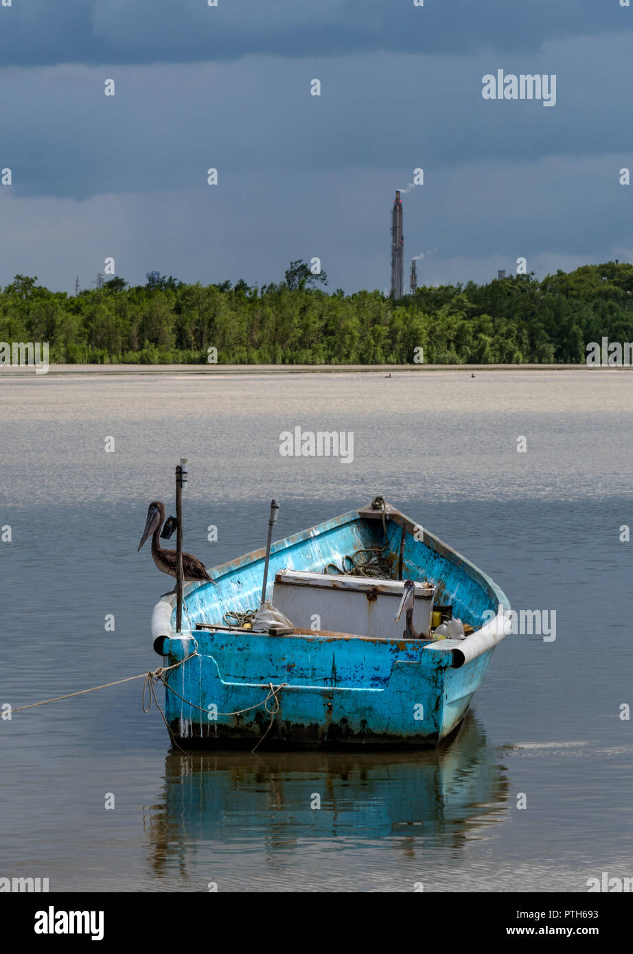 Un Pellicano si siede su una barca da pesca nel fango appartamenti come un imminente tempesta si chiude. Foto Stock