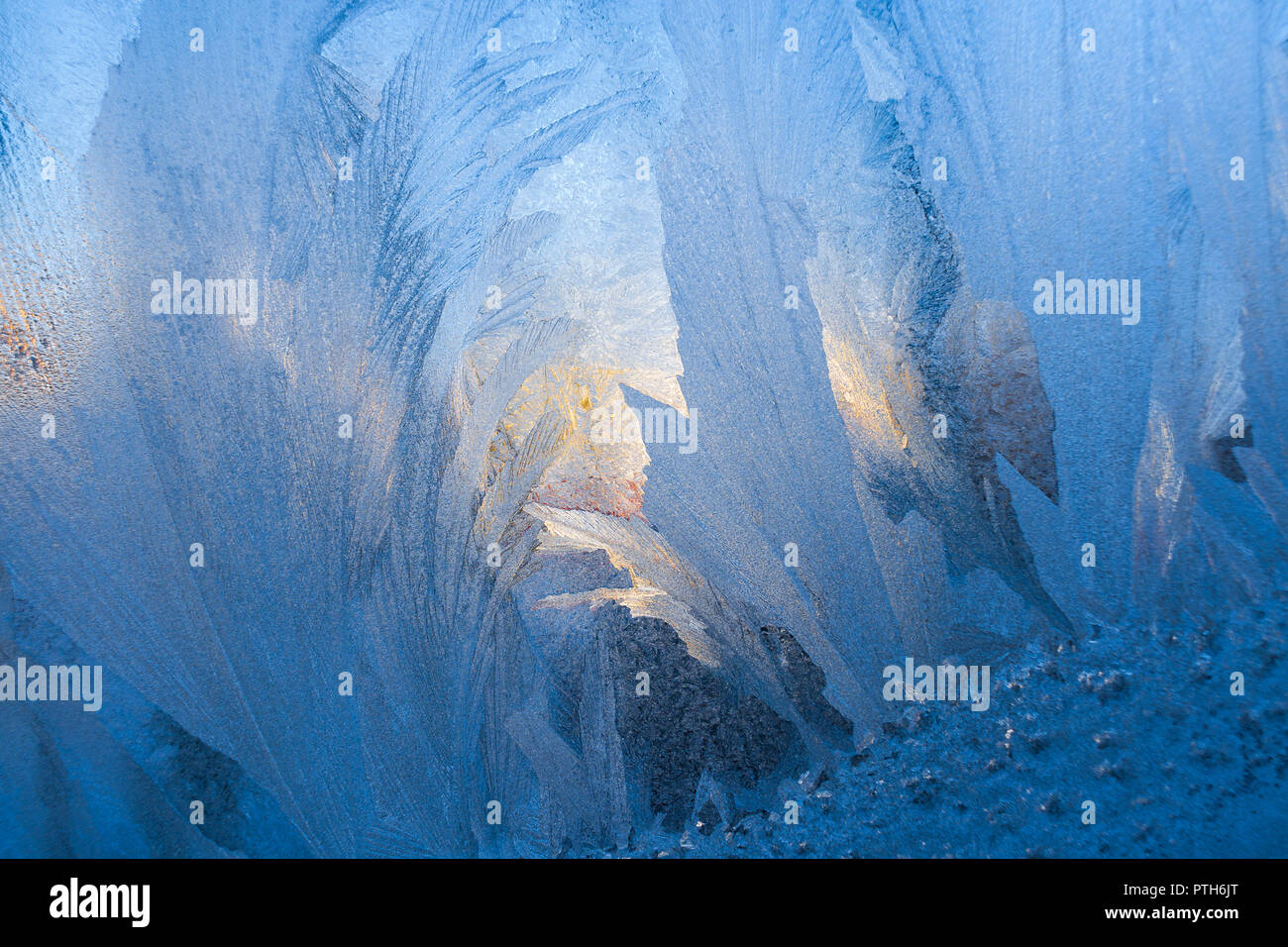 Close-up frosty blu pattern simile come piume e sole invernale sulla lastra di vetro. Foto Stock
