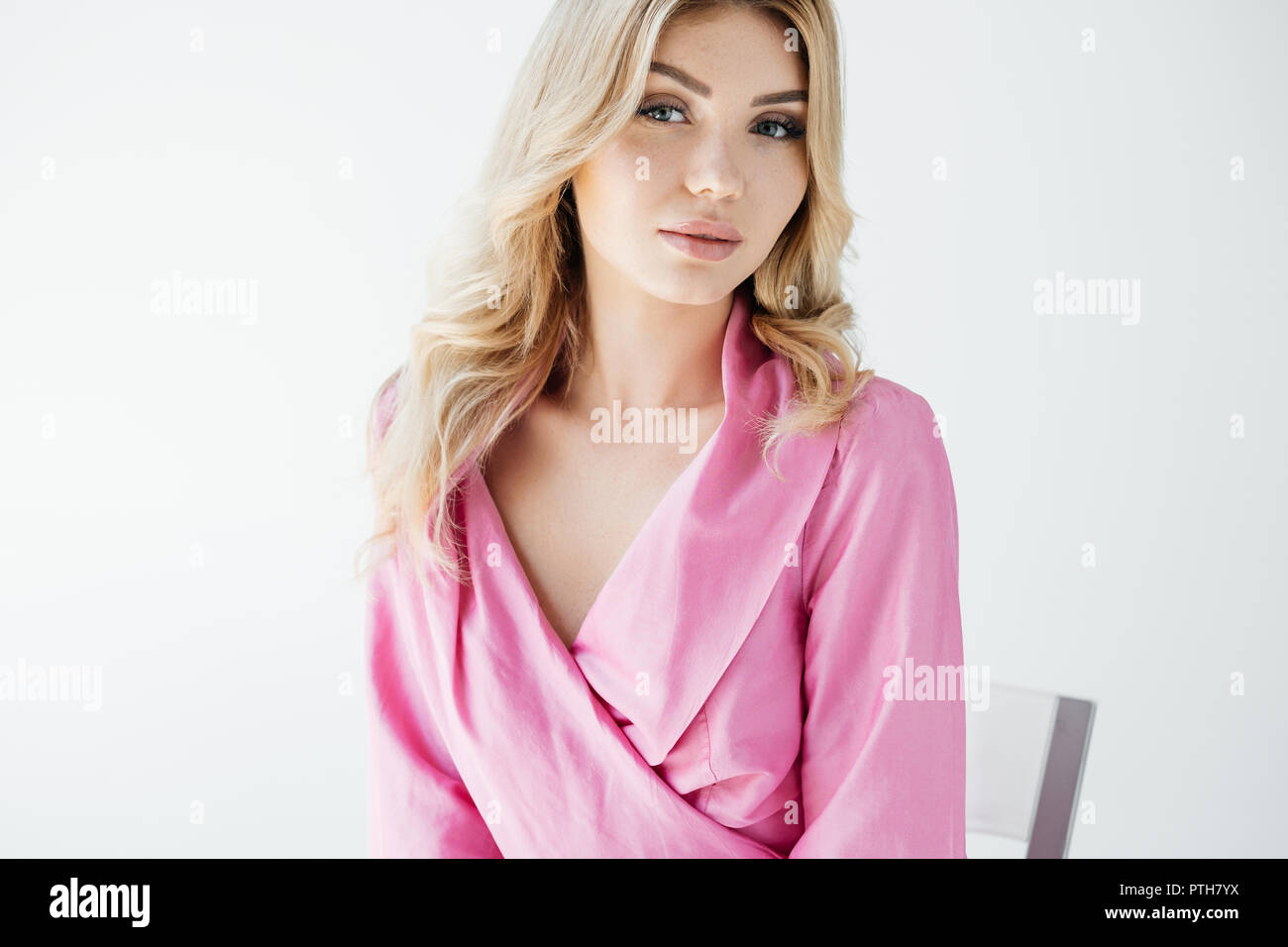Ritratto di attraente giovane donna in rosa camicetta in posa su sfondo bianco Foto Stock