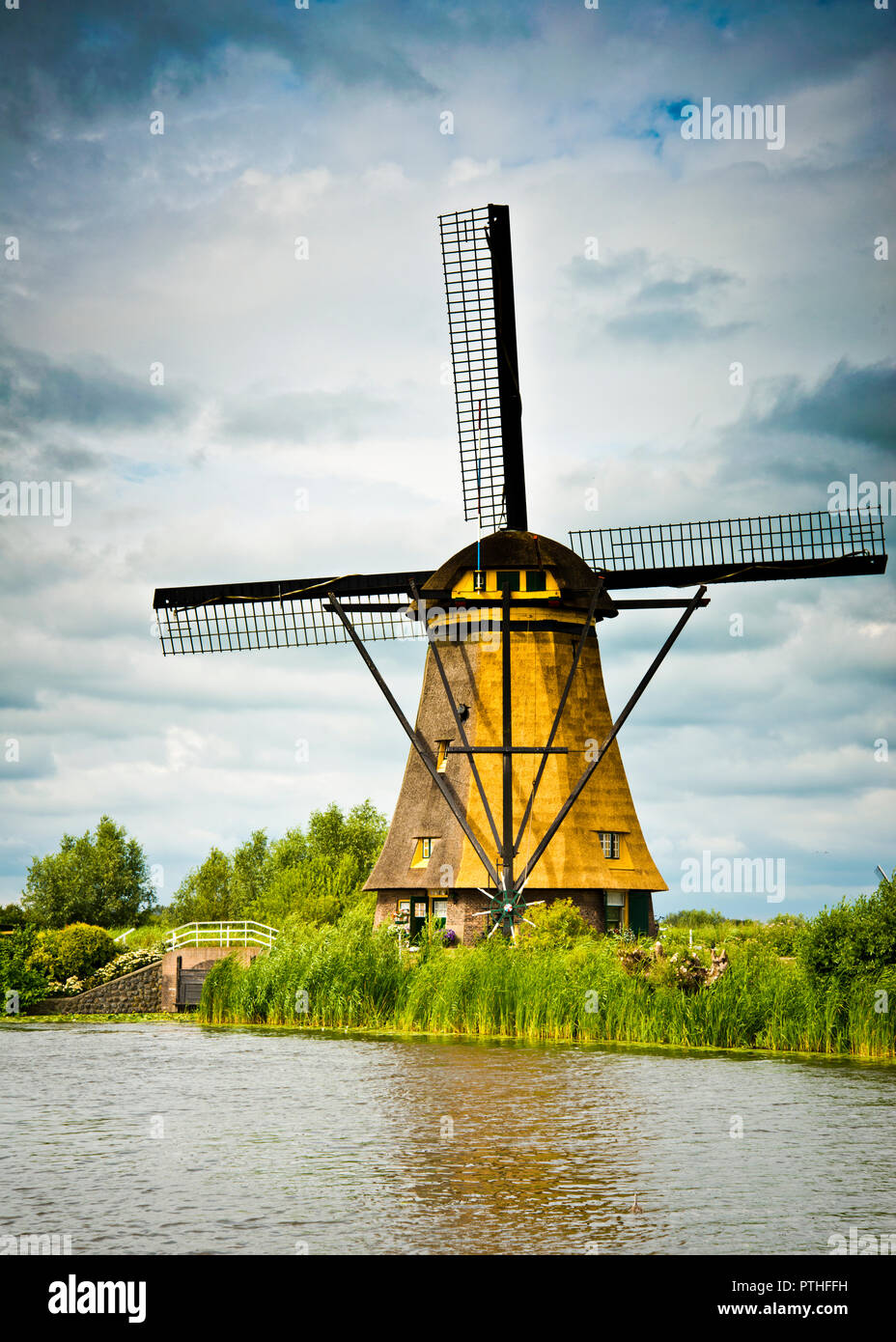 Tradizionale mulino olandese con paglia sulla riva del canale, contro un blu, graduato cielo nuvoloso, Kinderijk, Olanda, Foto Stock