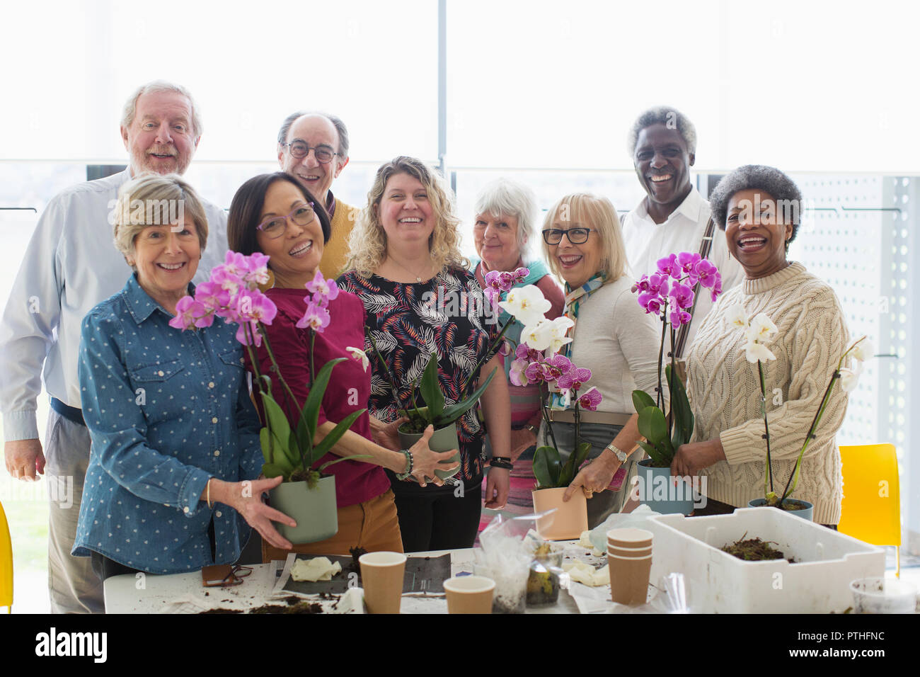 Ritratto sorridente seniors attiva godendo di decorazione floreale di classe Foto Stock