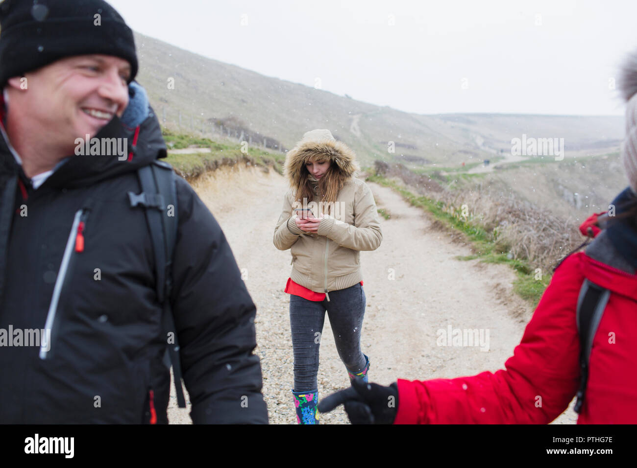 Famiglia in un abbigliamento caldo camminando sul telecomando nevoso inverno percorso Foto Stock