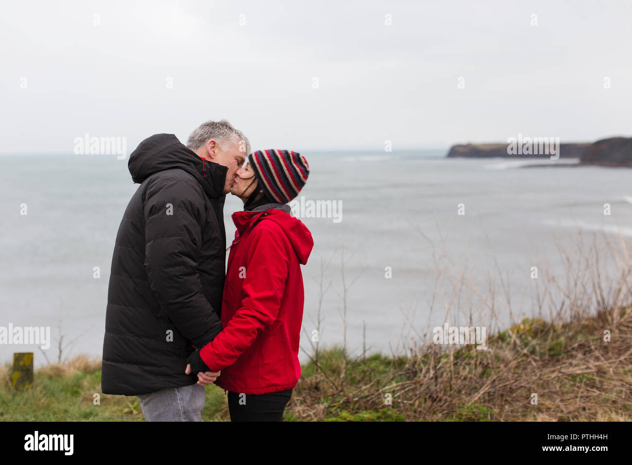 Coppia affettuoso bacio sulla scogliera con vista sull'oceano Foto Stock