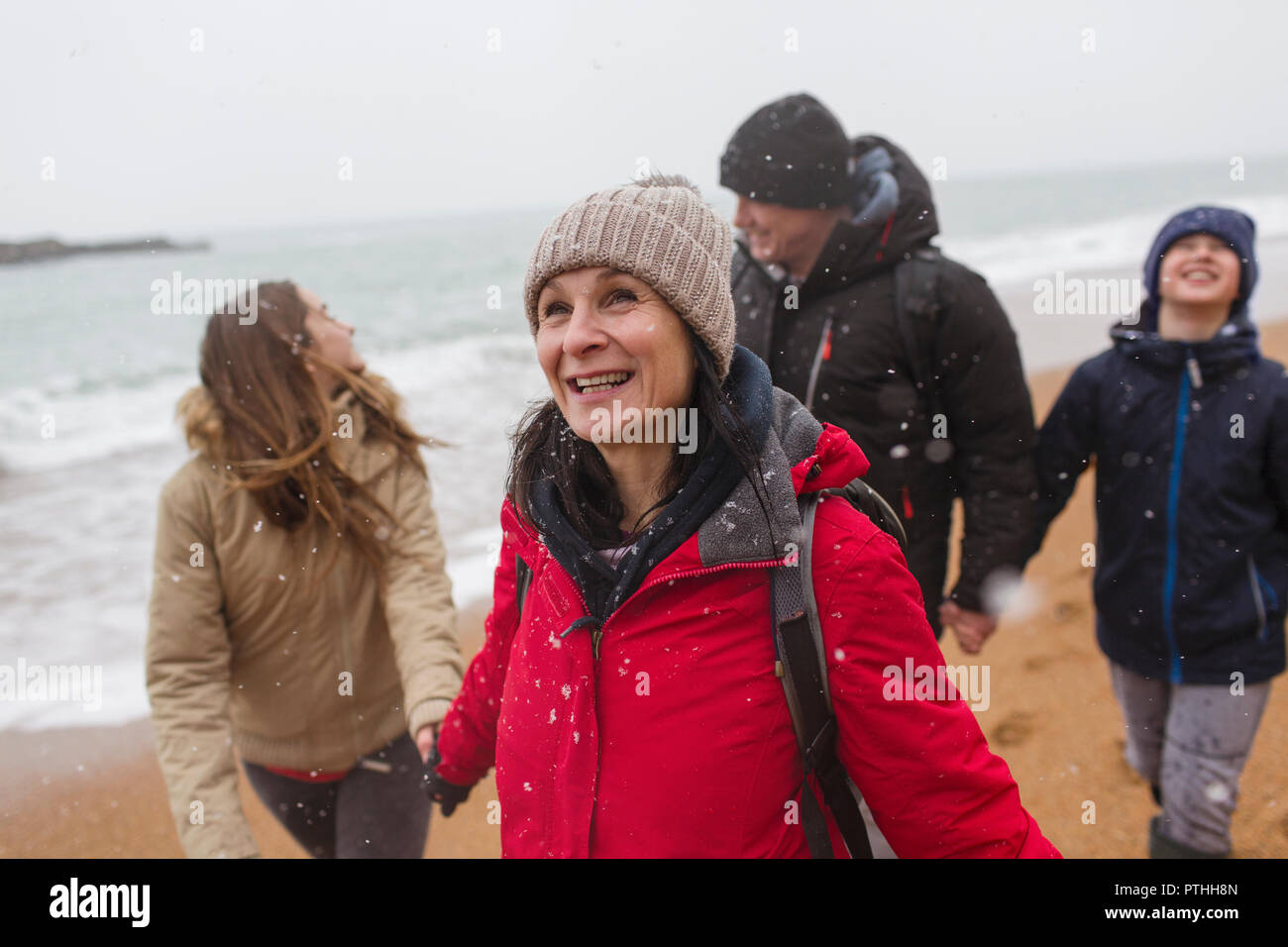 La caduta della neve sulla famiglia felice sulla spiaggia invernale Foto Stock