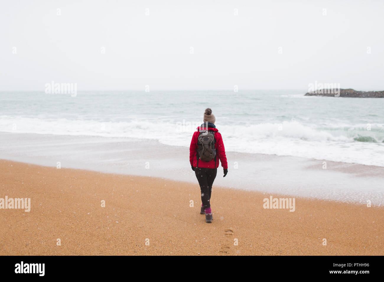 Donna con zaino camminando sulla spiaggia invernale Foto Stock
