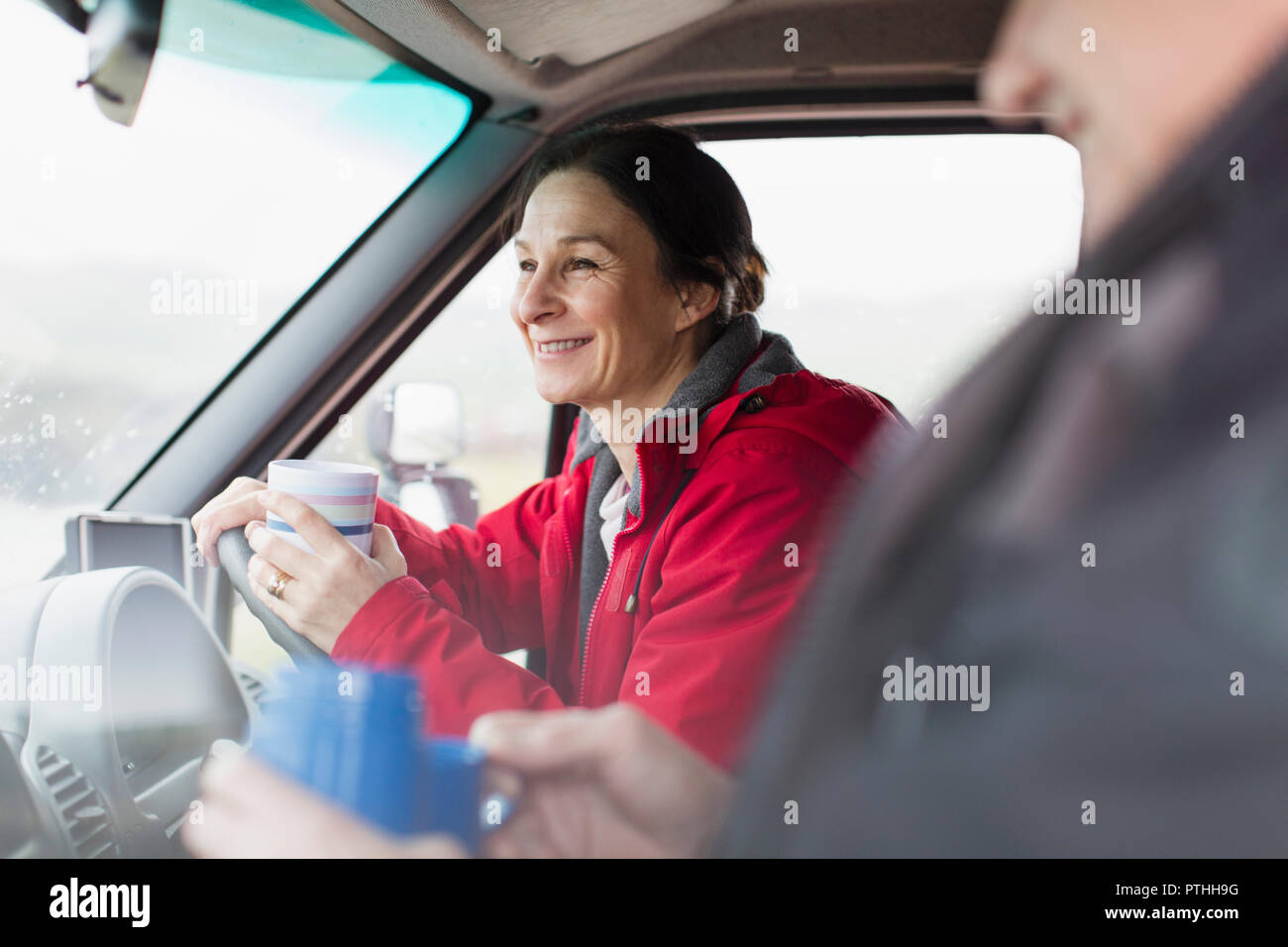 Donna sorridente di bere il caffè e il motore di guida home Foto Stock