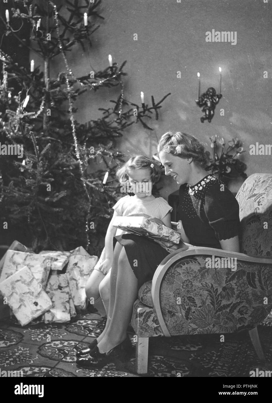 Natale nel 1940s. Una madre e figlia è seduto in poltrona con l'albero di natale. Regali di natale sono giacente al di sotto di esso. La Svezia 1940s Foto Stock