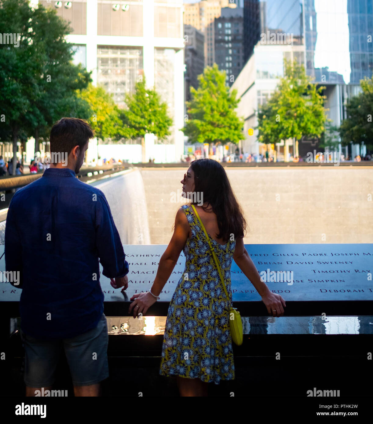Una giovane coppia in conversazione mentre pagando i loro rispetti al 9/11 World Trade Center Memorial fontane in Lower Manhattan, New York City Foto Stock