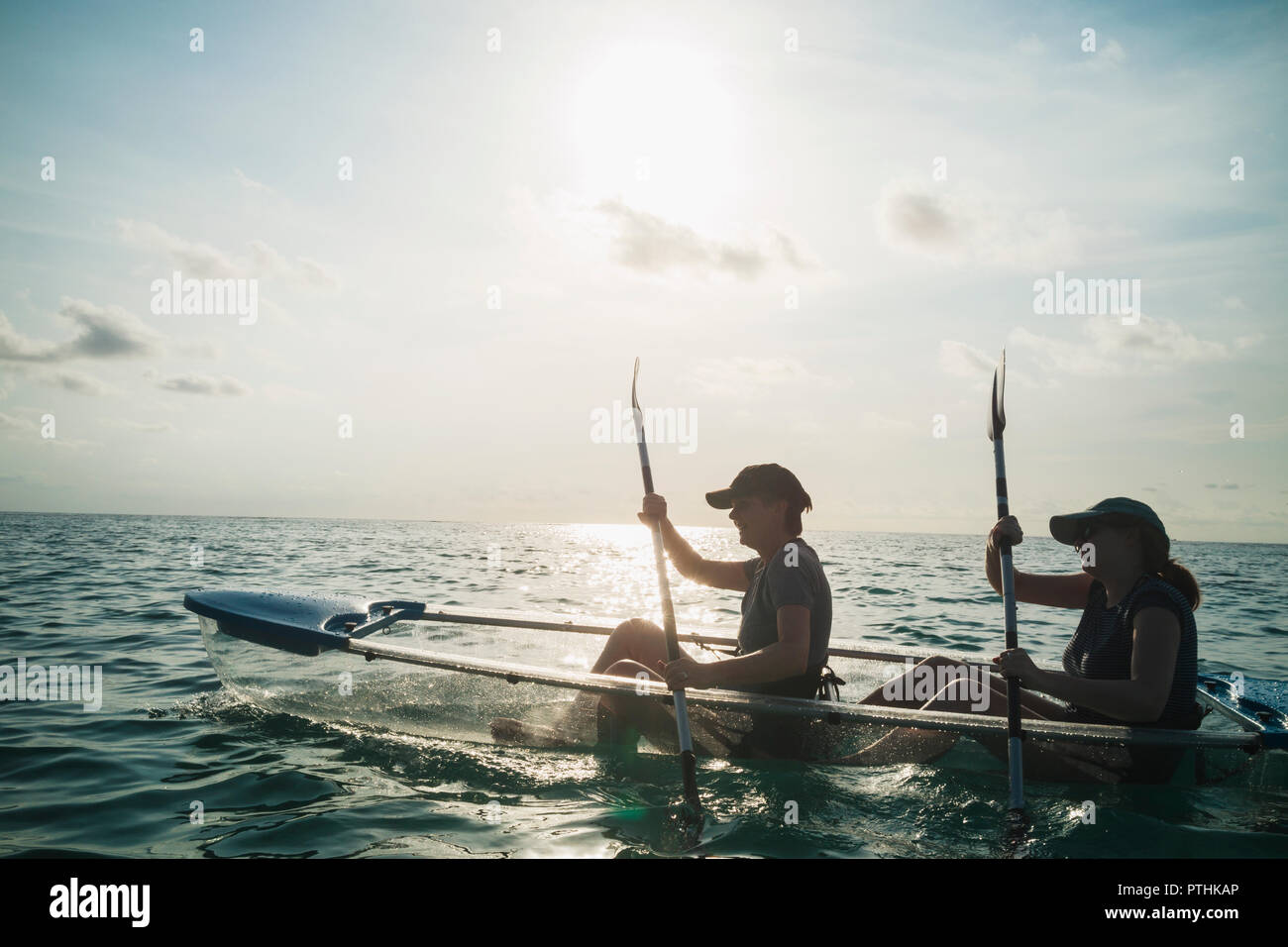 Le donne in fondo trasparente in canoa sull oceano soleggiato, Maldive, Oceano Indiano Foto Stock