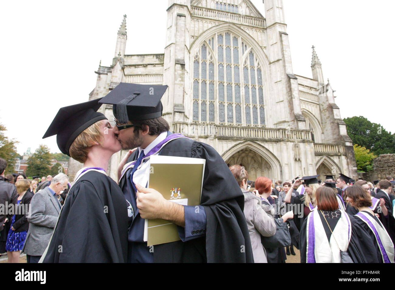 Un appena laureato giovane celebrare con un bacio dopo la loro cerimonia di laurea in Hampshire, Inghilterra. Foto Stock