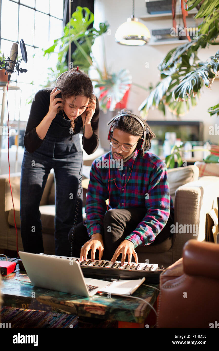 Giovane uomo e donna la registrazione della musica, suonare la tastiera pianoforte in appartamento Foto Stock