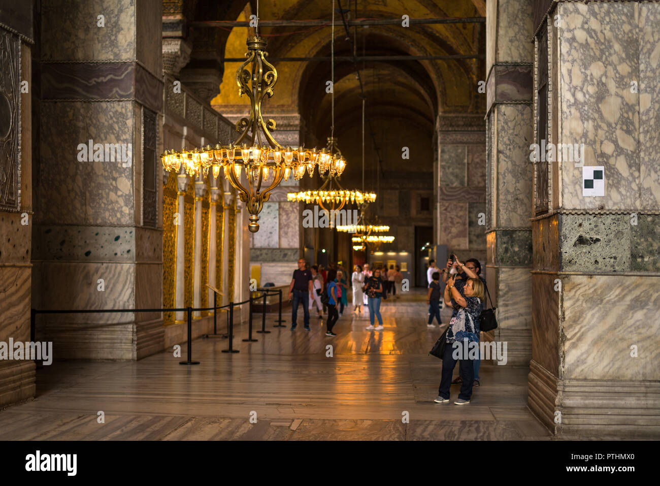 I turisti per scattare delle foto di uno dei molti lampadari ornamentali all'interno il Museo Hagia Sophia, Istanbul, Turchia Foto Stock