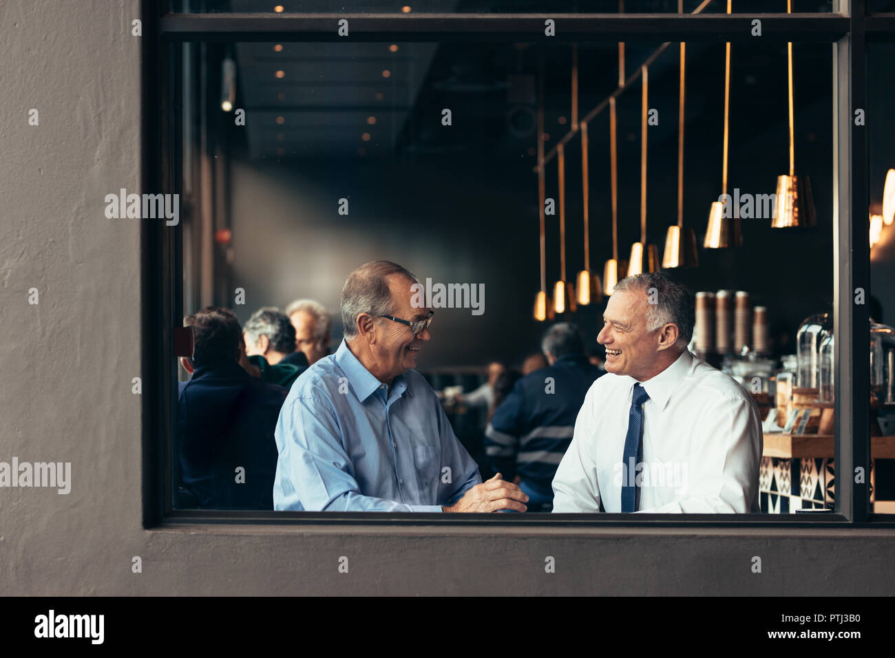 Due partner commerciali aventi una discussione informale presso il cafe dopo il lavoro. Felici gli imprenditori senior parlando e sorridente in un ristorante. Foto Stock