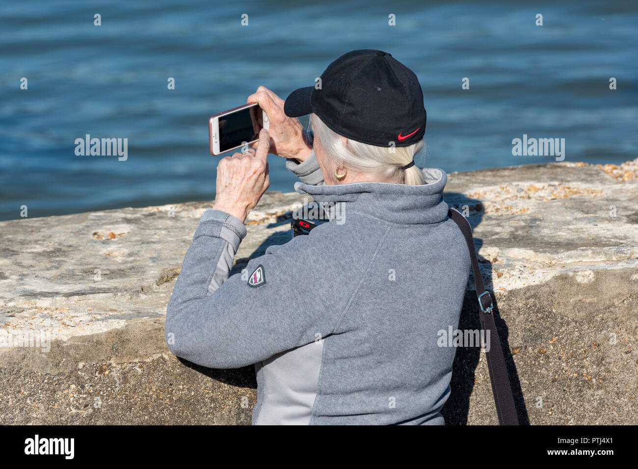 Più anziani o persone di mezza età silver surfer o donna lady utilizzando uno smartphone o un dispositivo mobile per scattare una fotografia o un'immagine. Foto Stock