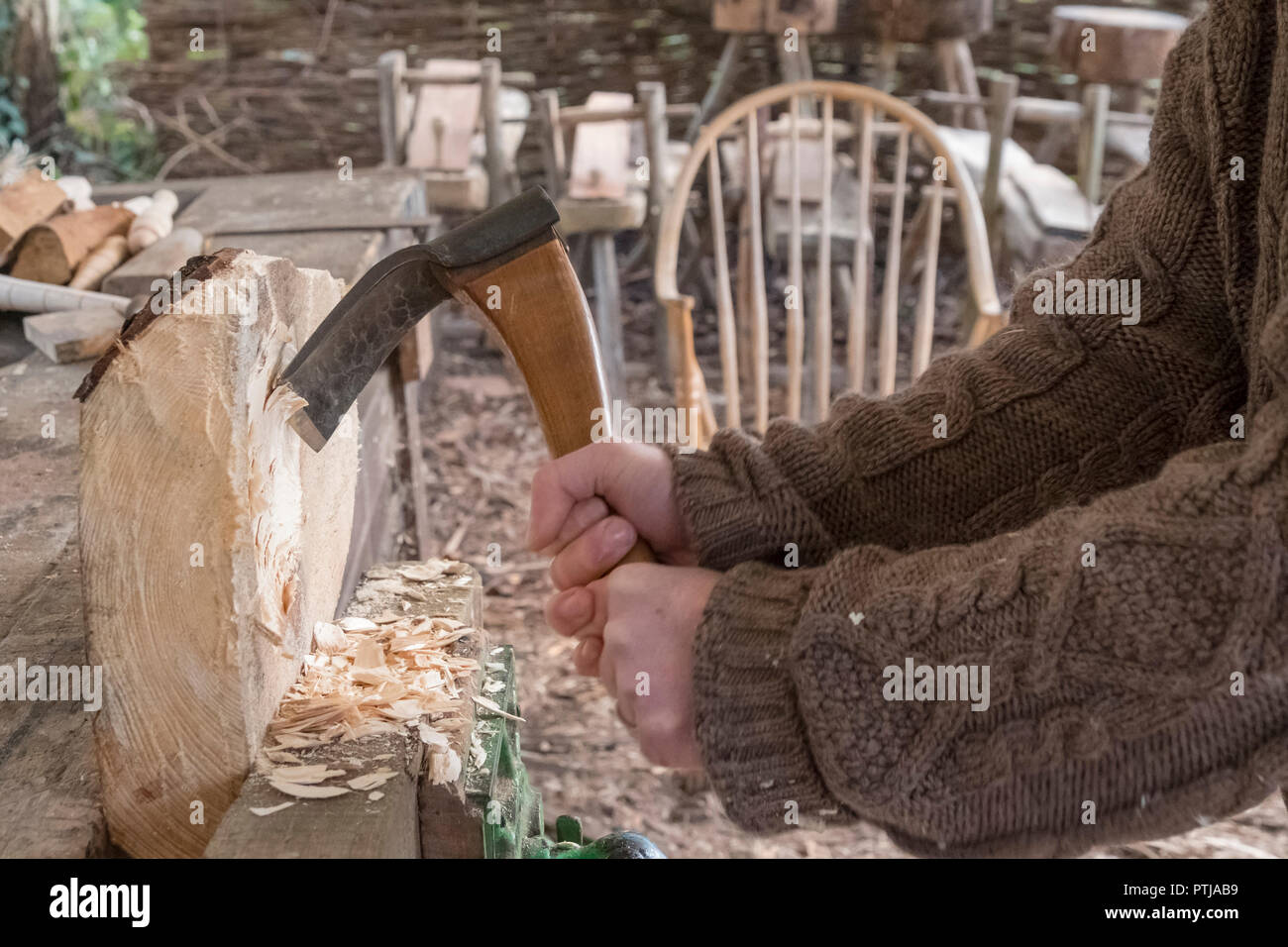 Usando una mano adze alla moda la sede per uno sgabello. Foto Stock