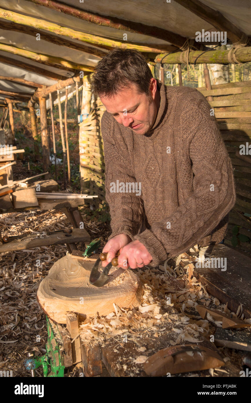 Utilizzando un scorp alla cava di un sgabello in legno sedile. Foto Stock