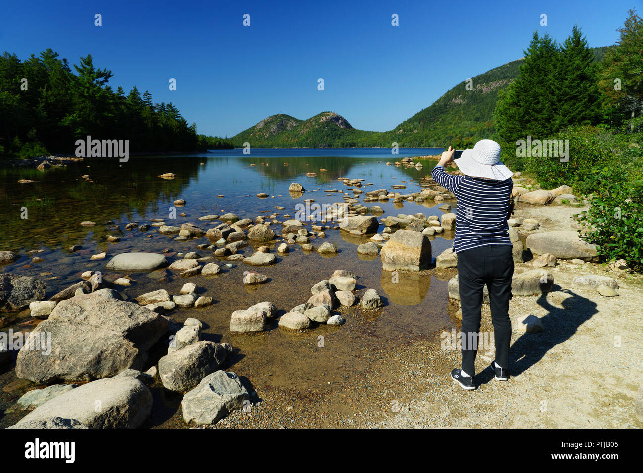 Donna di scattare una foto di Jordan Pond con il suo telefono cellulare.Parco Nazionale di Acadia, Maine, Stati Uniti d'America. Foto Stock