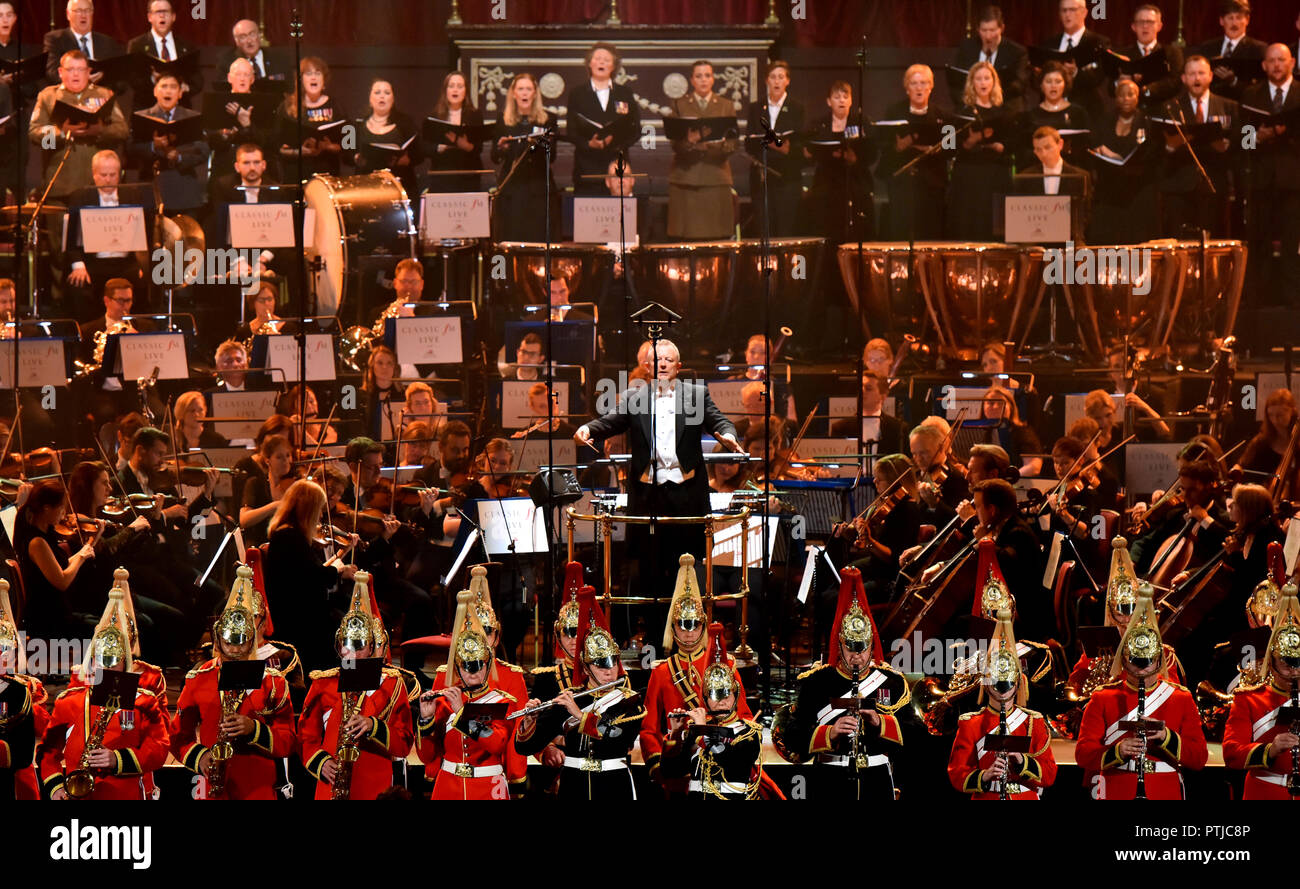 Patrick Hawes conduce la Royal Philharmonic Orchestra, la banda della cavalleria della famiglia, il corpo dei tamburi di Sua Maestà la Royal Marines e la fanfara Team della banda della Royal Air Force sul palco al Classic FM evento dal vivo presso la Royal Albert Hall di Londra. Foto Stock