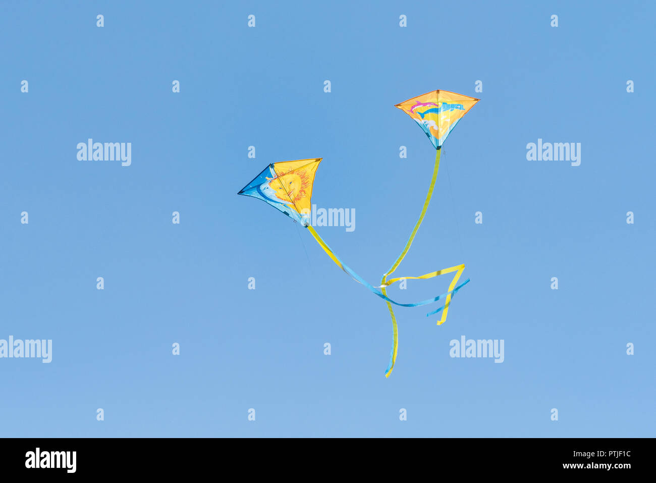 Due coloratissimi aquiloni volare contro un cielo blu senza nuvole. Foto Stock