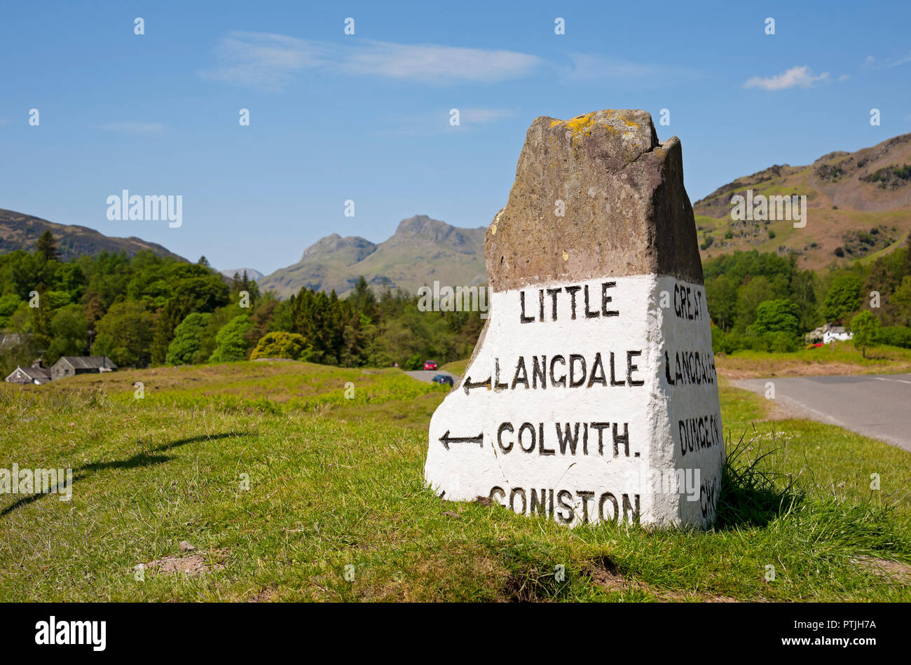 Stone Road Sign vicino a Elterwater con Langdale Pikes in background. Foto Stock