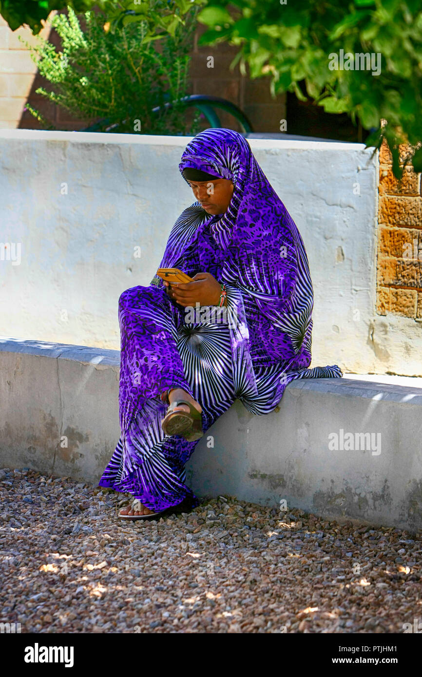 Giovane donna musulmana di colore indossa abbigliamento tradizionale udienza con il suo cellulare in Tucson AZ Foto Stock