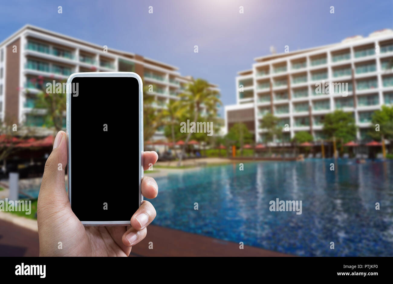 Mano d'uomo mostra mobile smartphone in posizione verticale mock up del modello e sfocato hotel sfondo per il tuo libro bussiness hotel. Foto Stock