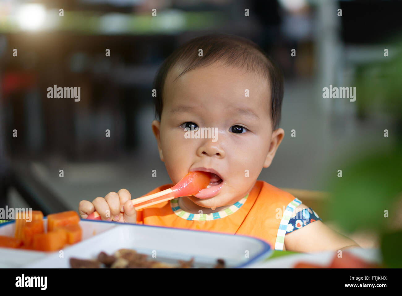 Asian Baby girl nel ristorante con un cucchiaio mangia il cibo. Foto Stock
