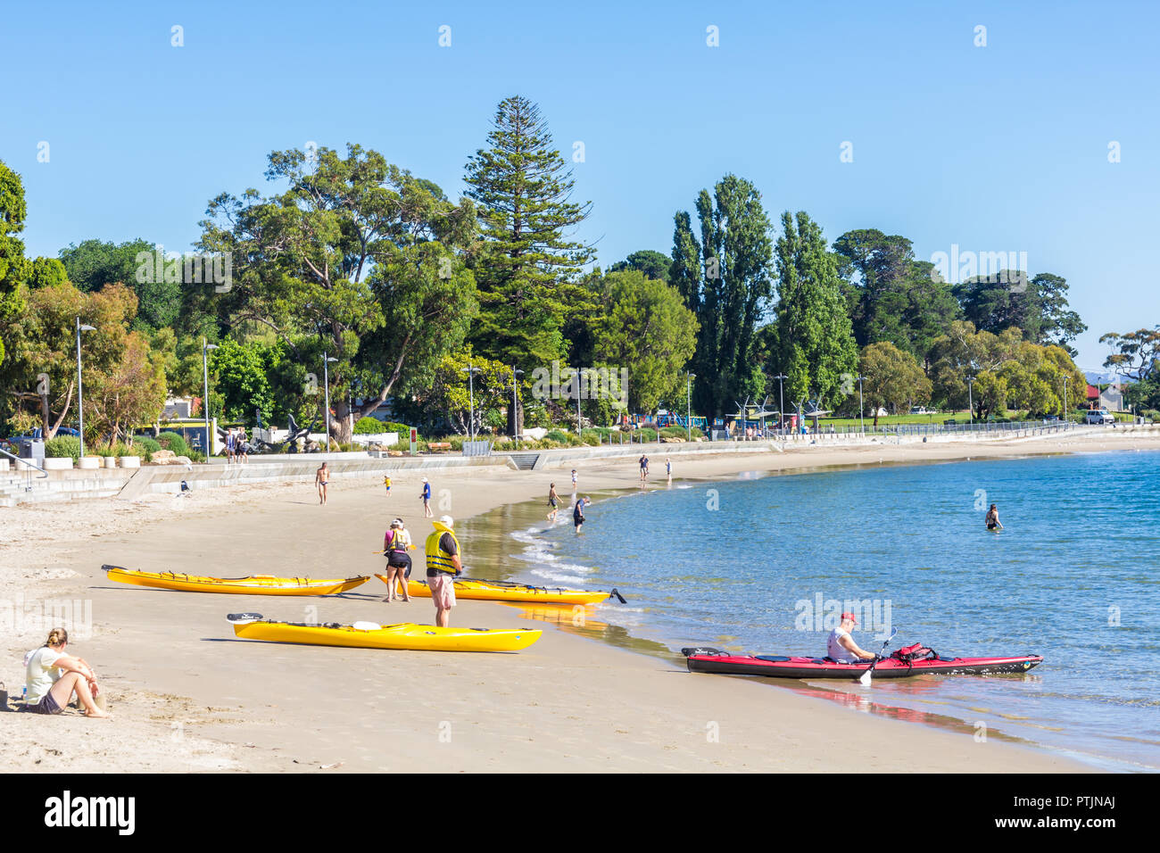 Lunga spiaggia di baia sabbiosa, Hobart, Australia - 7 January 2017: sunny beach con i nuotatori e mare kayakers circa per andare per un dispositivo di compressione Foto Stock