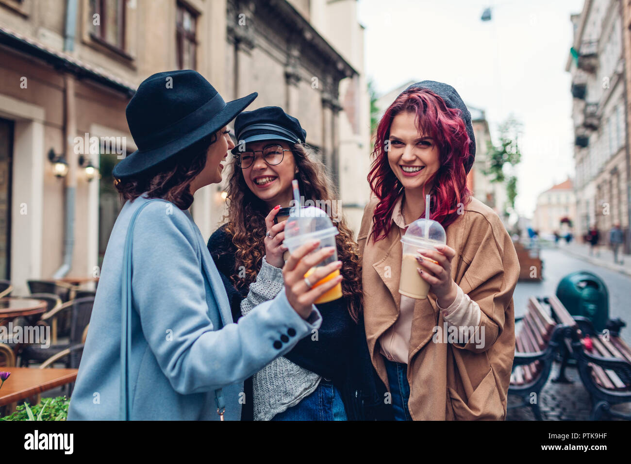 Tre amici di sesso femminile avente un drink all'aperto. Le donne il tintinnio caffè, succo d'arancia e tazze di tè Foto Stock