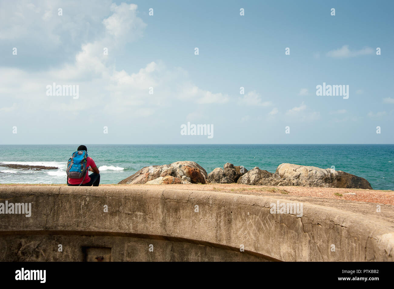 Viaggiatore seduto su una parete che guarda al mare dai bastioni, Galle Fort , Sri Lanka Foto Stock