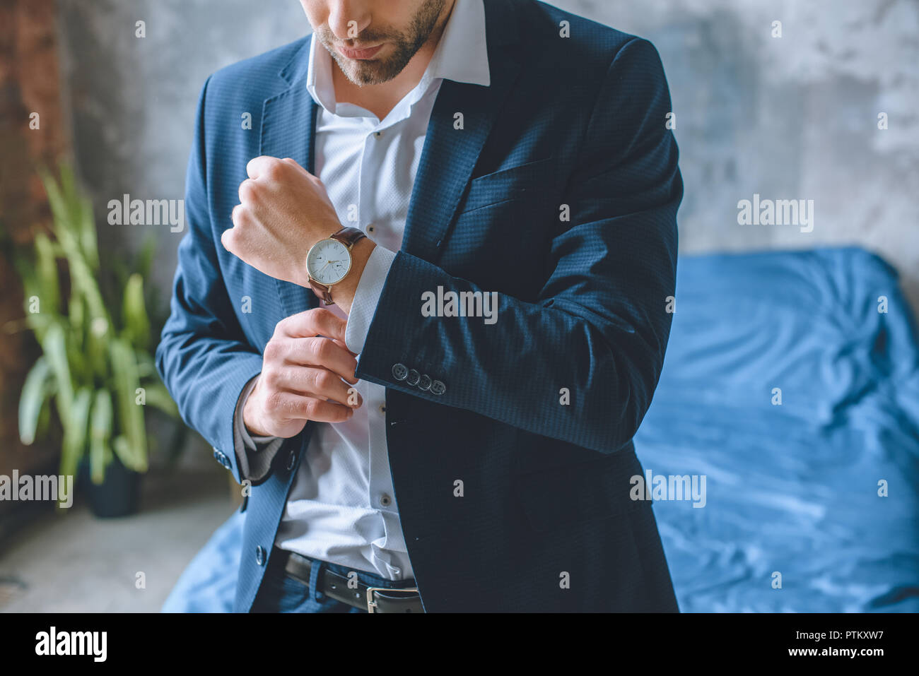 Immagine ritagliata di imprenditore in tuta di mettere su un orologio da polso in camera da letto a casa Foto Stock