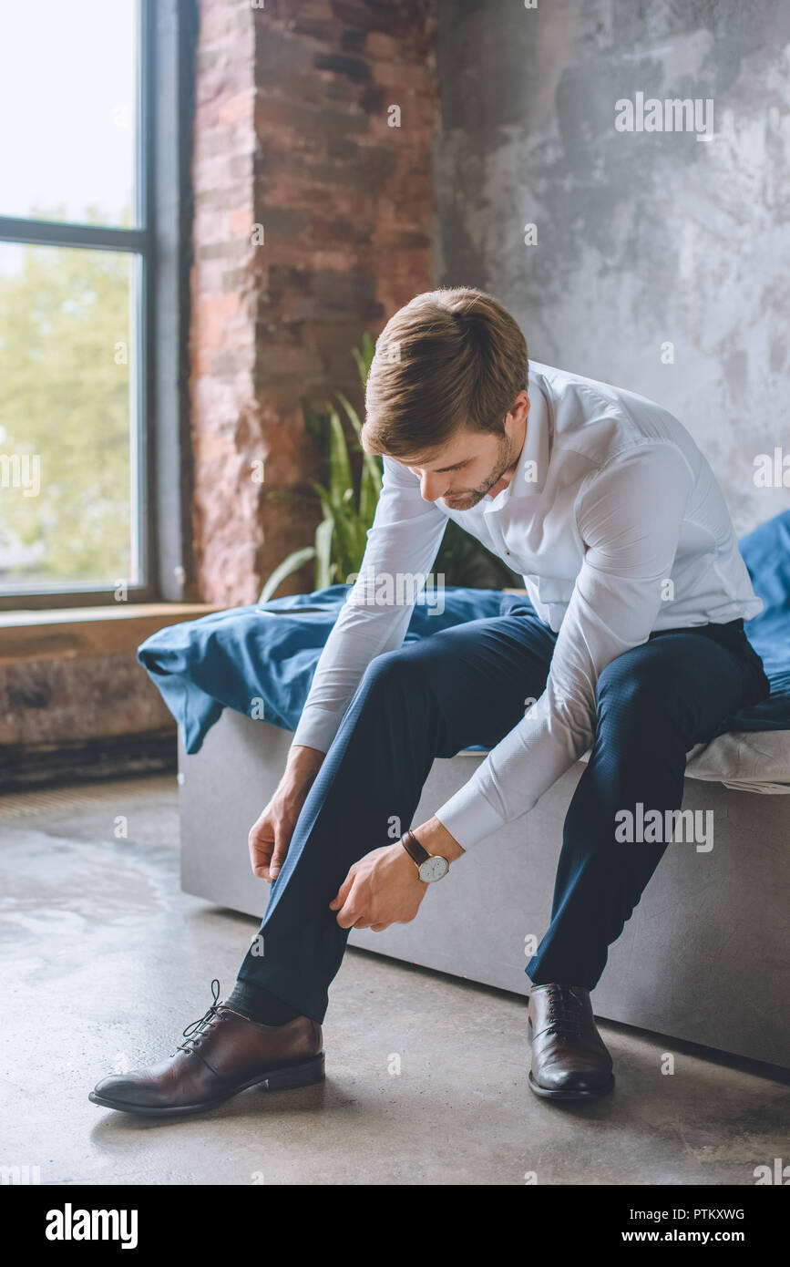 Giovane imprenditore lacci delle scarpe di legatura in camera da letto a casa Foto Stock