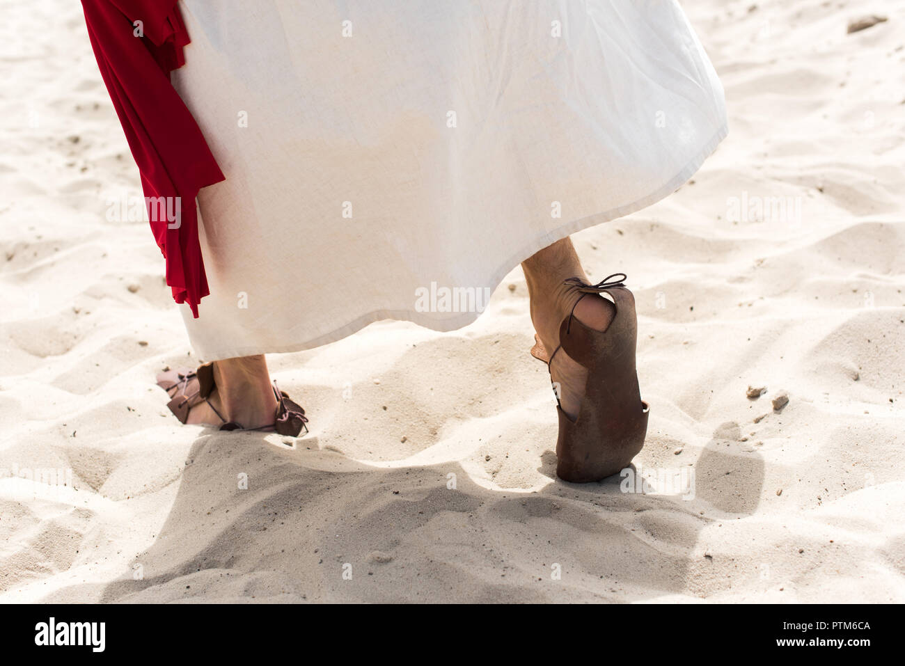 Immagine ritagliata di Gesù in accappatoio e sandali e anta rosso camminare  sulla sabbia nel deserto Foto stock - Alamy