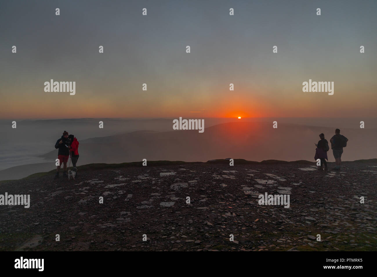 Pen y ventola, Brecon Beacons, Wales, Regno Unito. Il 10 ottobre 2018. Hill walkers godono di una drammatica sunrise dal picco del Pen y Fan, la montagna più alta nel sud della Gran Bretagna si trova in Brecon Beacons. Su ciò che è previsto per essere una calda e luminosa giornata autunnale con temperature in Galles del Sud previsto a picco su 21gradi celsius. Credito: Haydn Denman/Alamy Live News Foto Stock